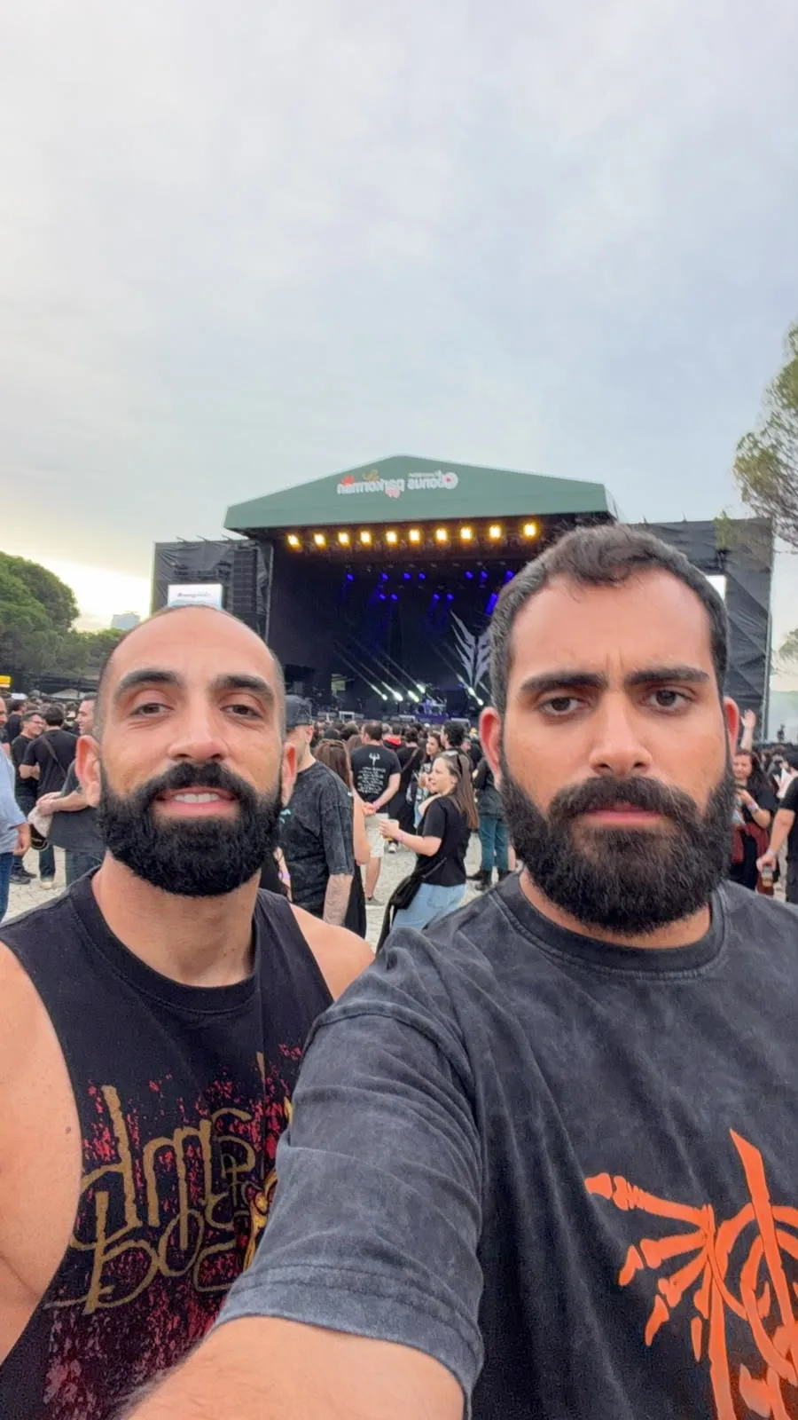 Two friends at an outdoor festival with the stage lit up behind them