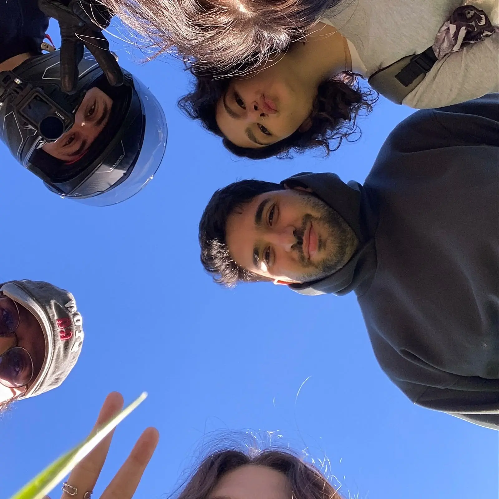 Four friends looking down at the camera against a clear blue sky